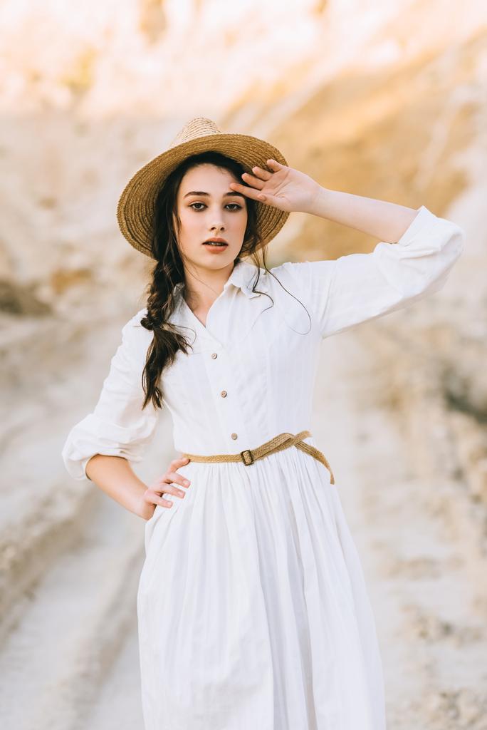 beautiful stylish girl in white dress and straw hat posing in sandy canyon - Photo, Image
