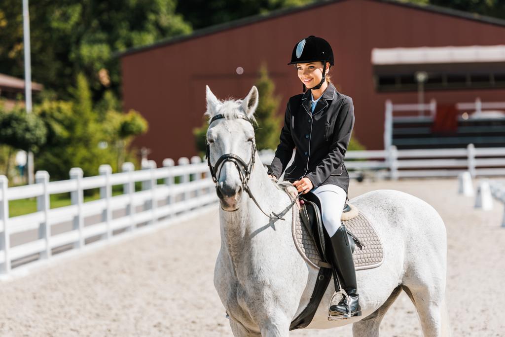 atrakcyjne uśmiechający się kobiece jeździectwo konna koni w horse club - Zdjęcie, obraz