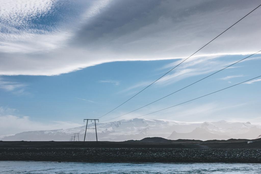 hermoso cielo icelandés sobre cables de alto voltaje y el río azul, Jokulsarlon, Islandia
 - Foto, Imagen