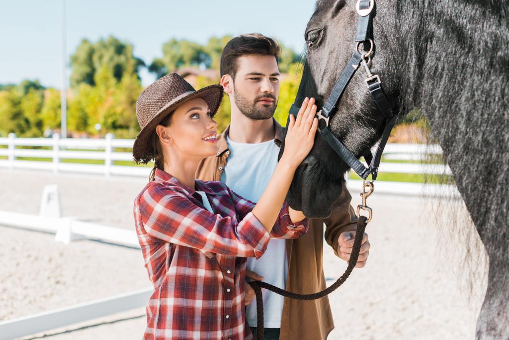 vaquero y vaquera en ropa casual palming caballo negro en el rancho
 - Foto, imagen