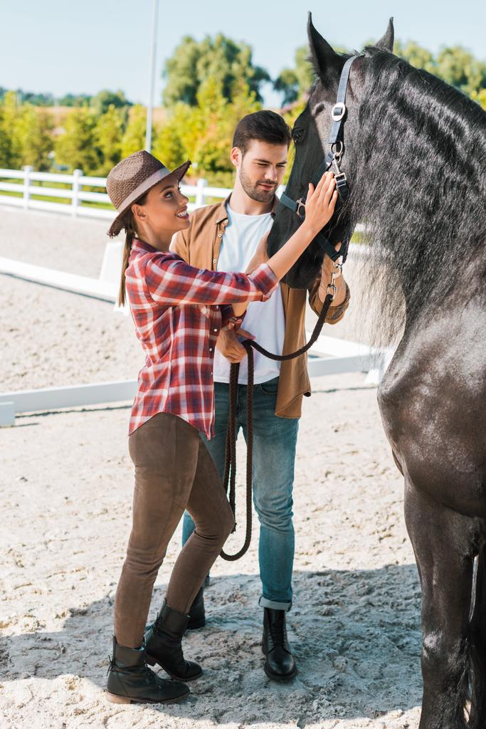 feminino e masculino jockeys palming preto cavalo no rancho
 - Foto, Imagem
