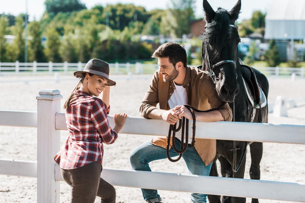 カウボーイとカウガールの馬とフェンスの近くに立って、牧場で話して笑みを浮かべてください。 - 写真・画像