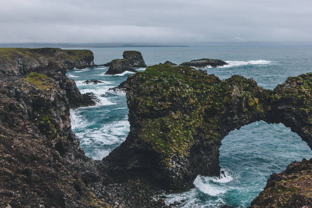 luonnonkaunis sammaleinen kallioita edessä sininen valtameri Arnarstapi, Islanti pilvinen päivä
 - Valokuva, kuva