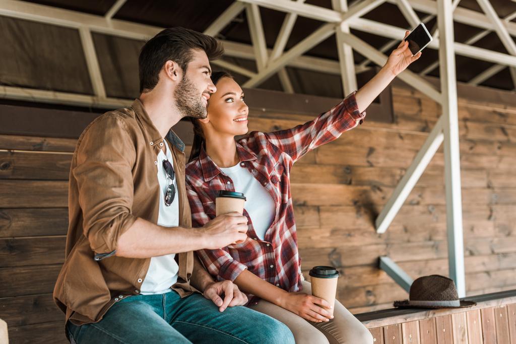 usmívající se kolegové s selfie s smartphone a kávu v papírových kelímků na ranči - Fotografie, Obrázek