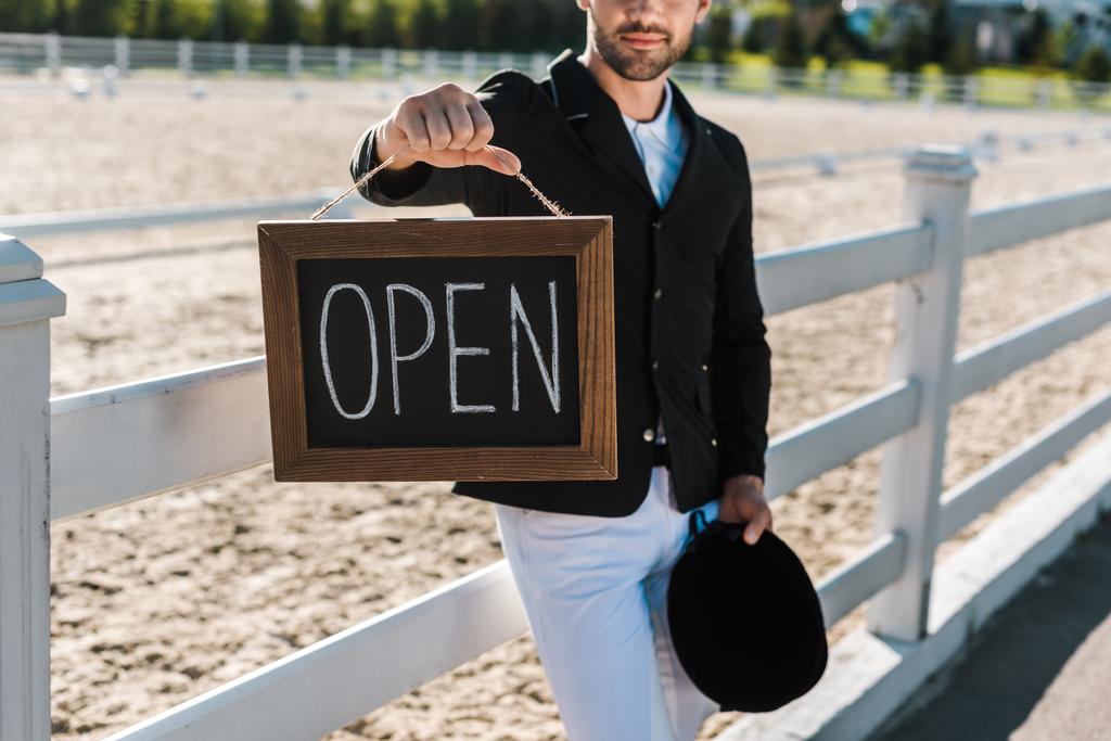 imagen recortada de hombre ecuestre apoyado en la valla y mostrando signo abierto en el club de caballos
 - Foto, imagen