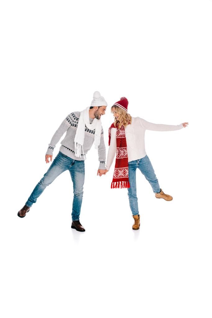 schönes junges Paar im winterlichen Outfit, Händchen haltend und einander lächelnd isoliert auf weiß - Foto, Bild