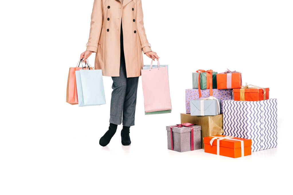 обрізаний знімок жінки, що тримає сумки для покупок і стоїть біля подарункових коробок ізольовано на білому
 - Фото, зображення