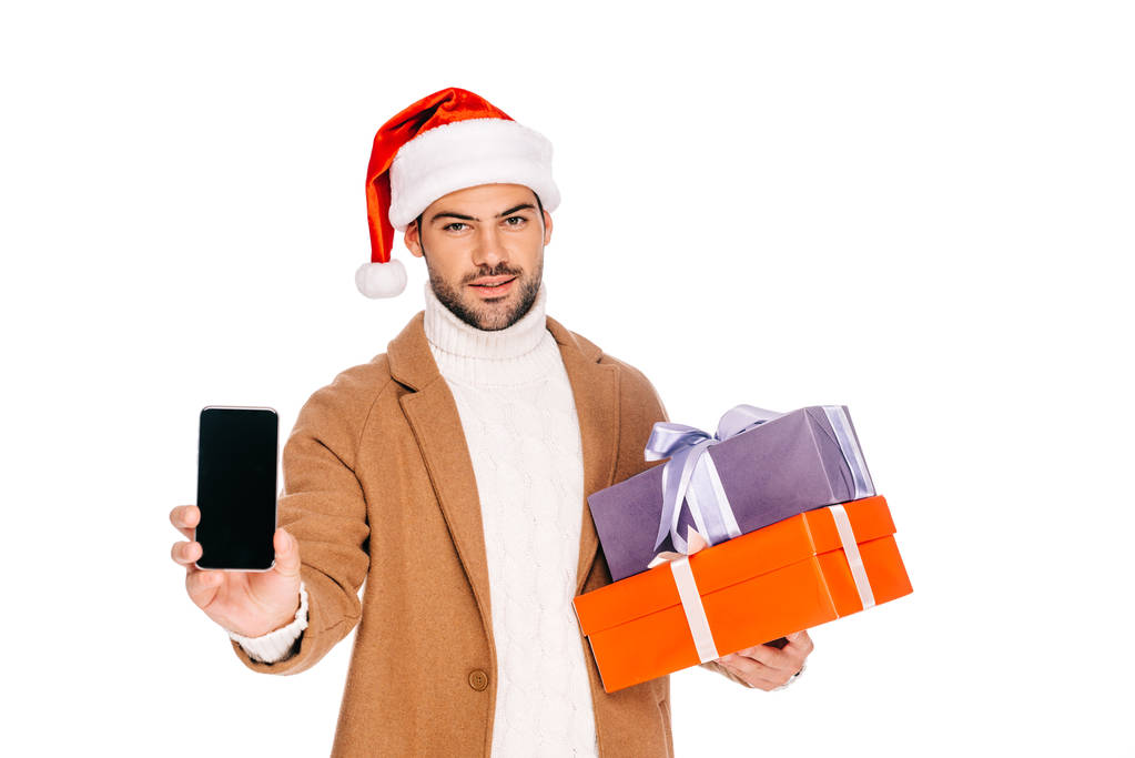 man in santa hat holding gift boxes and smartphone with blank screen isolated on white - Photo, Image