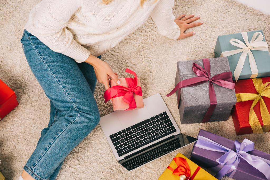 plan recadré de jeune femme tenant cadeau de Noël et en utilisant un ordinateur portable
 - Photo, image