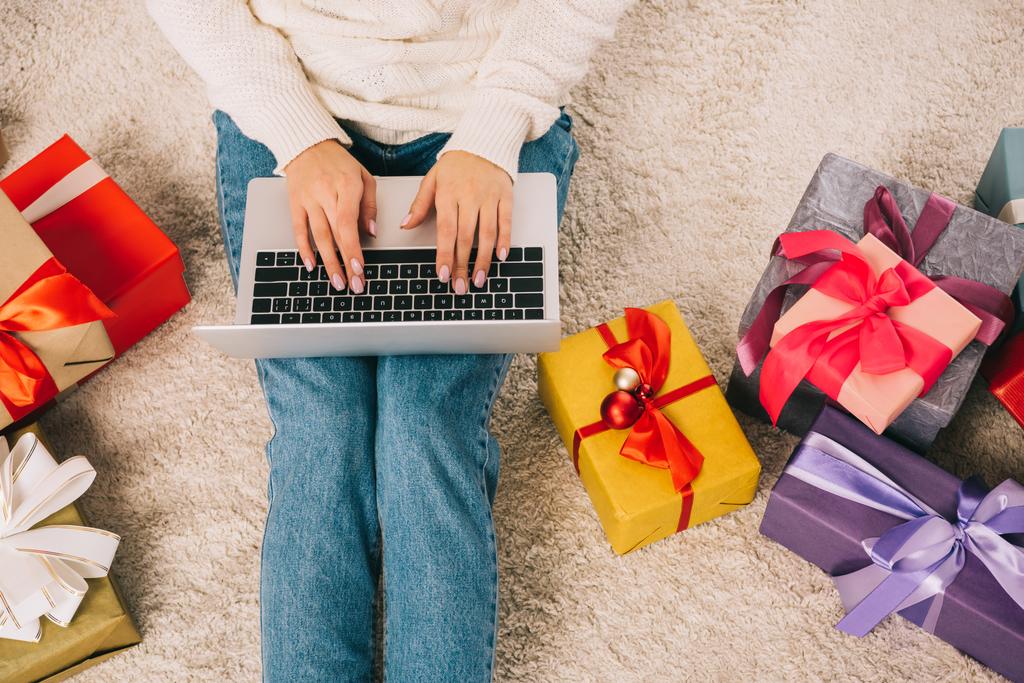 recortado disparo de mujer joven usando el ordenador portátil mientras está sentado cerca de regalos de Navidad
 - Foto, imagen