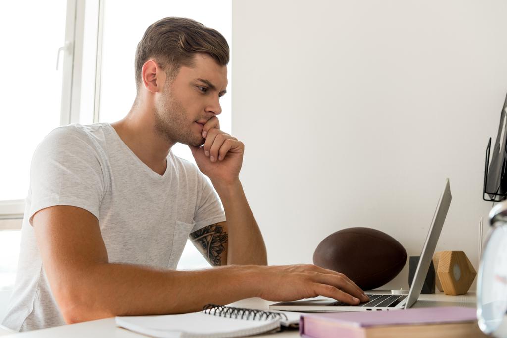 side view of focused man using laptop at table at home office - Photo, Image