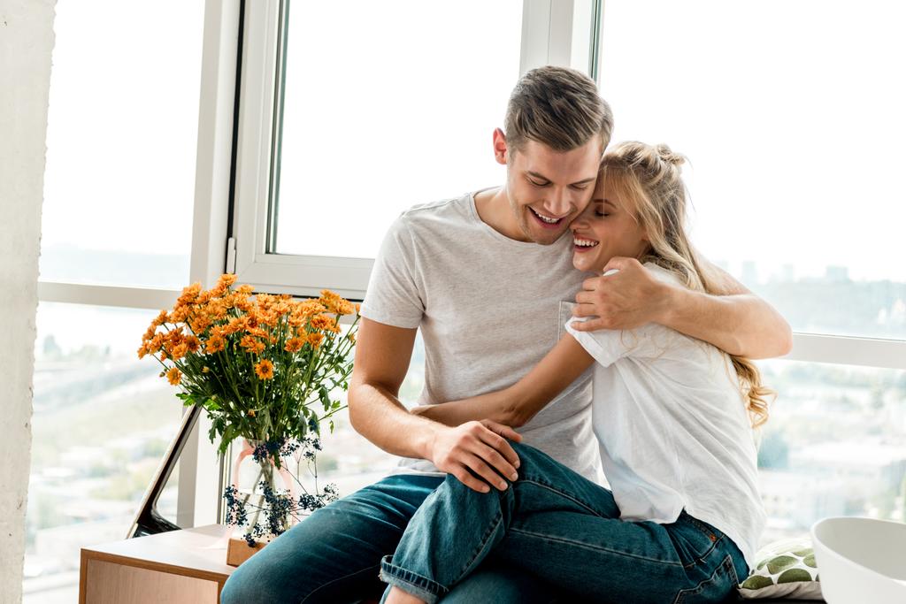 Szczęśliwa Młoda para zakochana w odzieży casual przytulanie w okno w domu - Zdjęcie, obraz