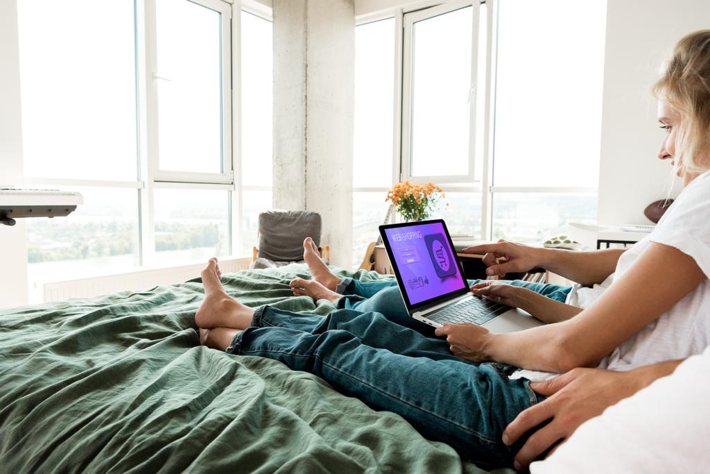 自宅のベッドで休んでいる間の画面上の文字をショッピングの web デジタル ノート パソコンを使用してカップルの部分的なビュー - 写真・画像