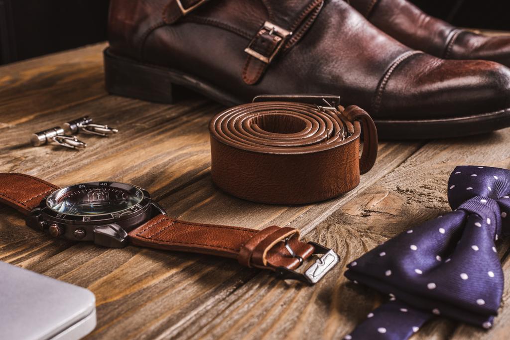 Close-up van lederen mannelijke accessoires en schoenen gerangschikt op houten tafelblad - Foto, afbeelding