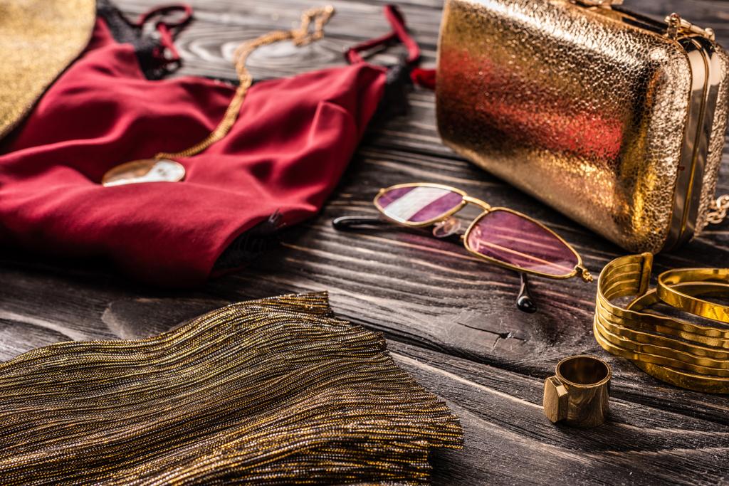 zblízka pohled uspořádání zlaté a červené módní ženský příslušenství a oblečení na dřevěný povrch - Fotografie, Obrázek