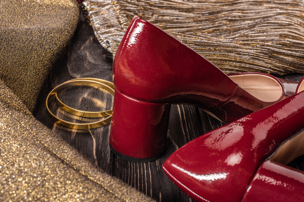 ahşap masa üzerinde şık kırmızı ve altın kadın ayakkabı ve bilezik görünümü kadar kapatın - Fotoğraf, Görsel