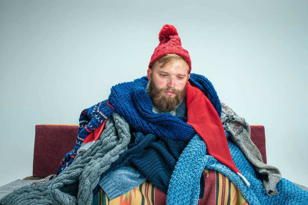 Hombre barbudo con chimenea sentado en el sofá en casa. Conceptos sanitarios
. - Foto, imagen