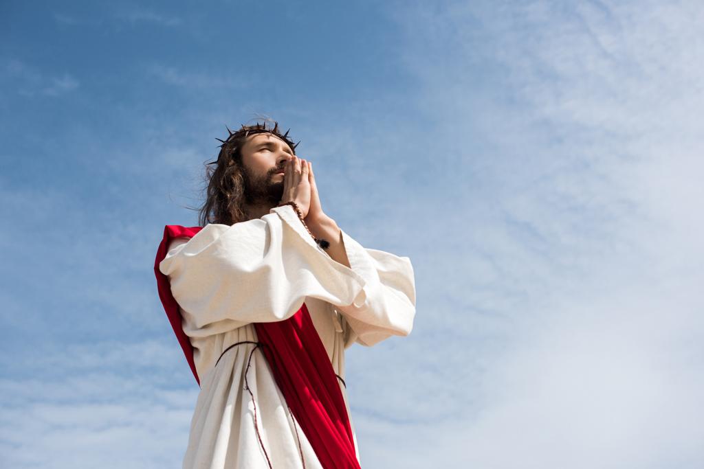niski kąt widzenia Jezus modląc się przeciw błękitne niebo - Zdjęcie, obraz