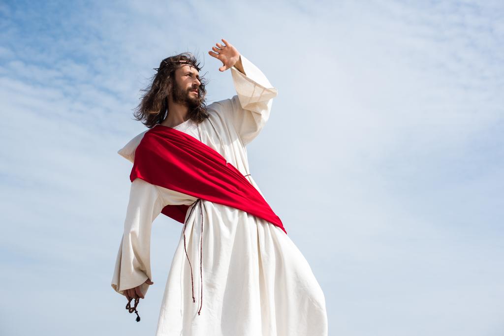 Иисус в мантии, красной ленте и терновом венце, держа четки и защищая лицо от света в пустыне
 - Фото, изображение