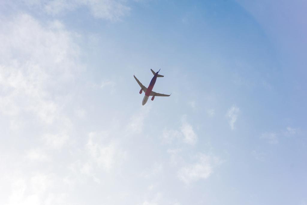 visão de baixo ângulo do avião voando no céu azul nublado
 - Foto, Imagem