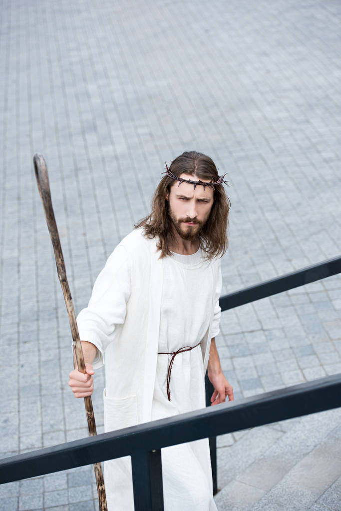 vue en angle élevé de Jésus en robe et couronne d'épines debout sur les escaliers avec le personnel
 - Photo, image