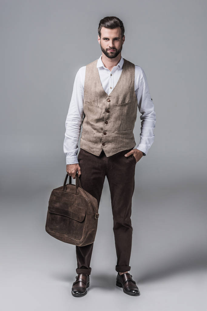 bell'uomo elegante in posa con borsa in pelle su grigio
 - Foto, immagini
