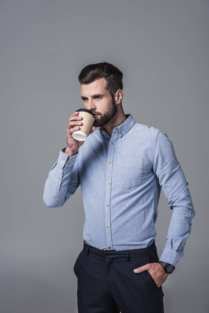 エレガントなスタイリッシュなビジネスマン グレーに分離された使い捨てのカップからコーヒーを飲む - 写真・画像