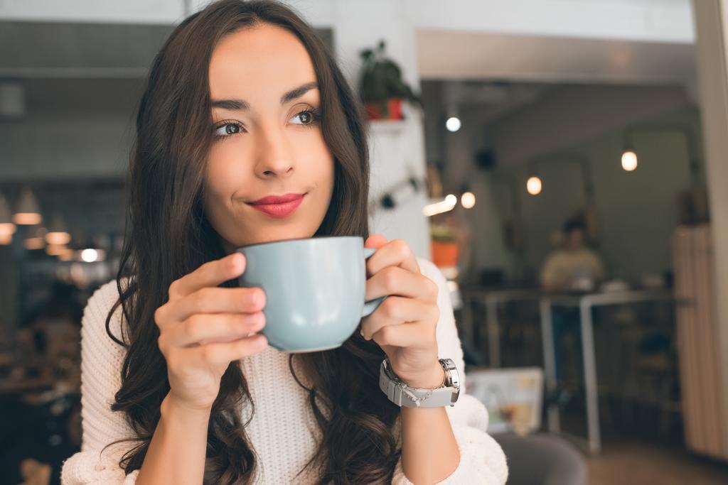 selective focus of young attractive woman drinking coffee at table in cafe - Photo, Image