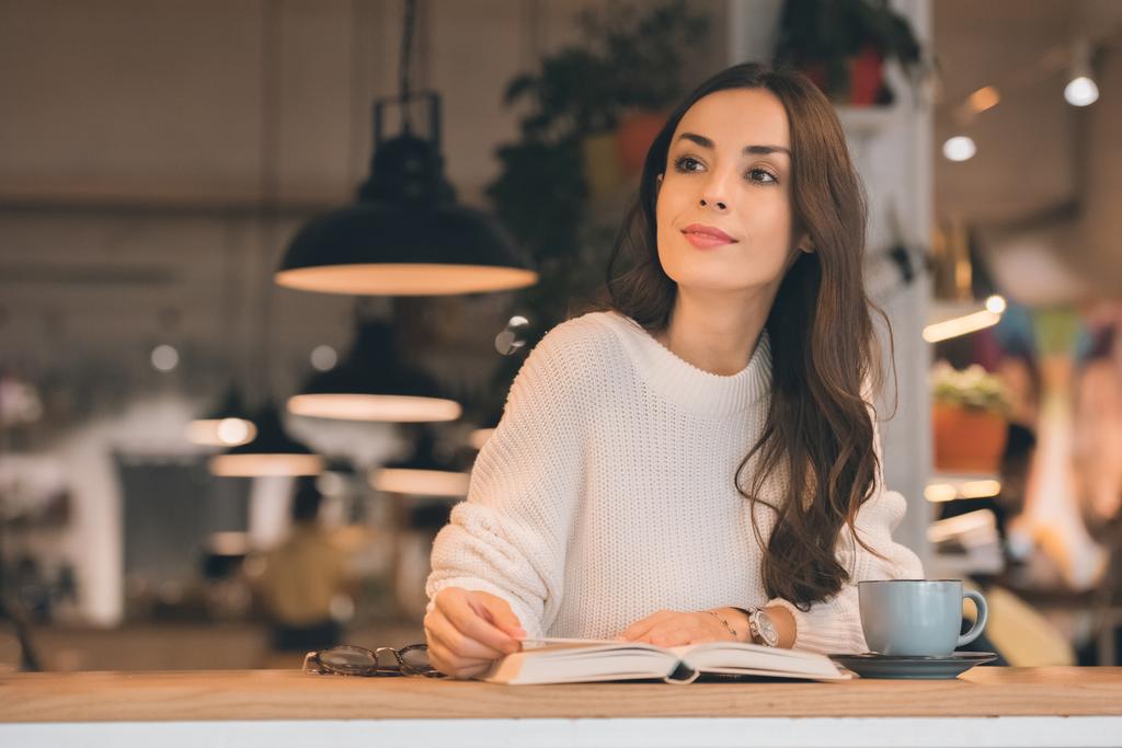 atractiva mujer leyendo libro en la mesa con taza de café en la cafetería
 - Foto, imagen