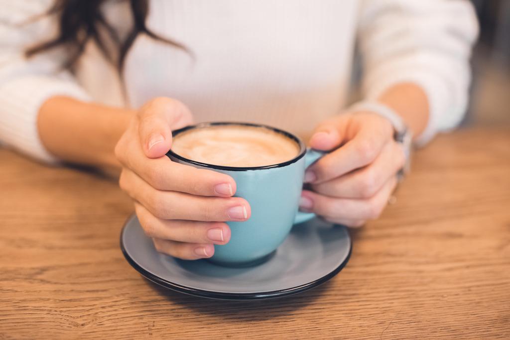 ořízne obraz žena sedí s šálek kávy v kavárně u stolu - Fotografie, Obrázek