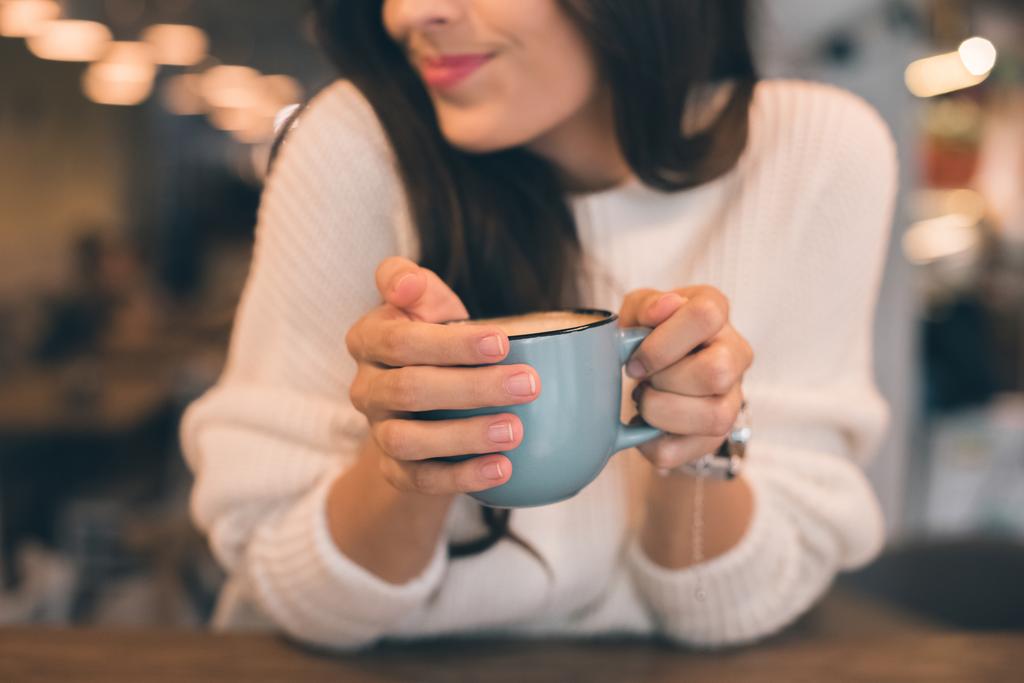 vista parziale della donna che tiene una tazza di caffè a tavola nel caffè
 - Foto, immagini