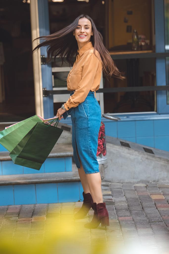 szczęśliwy szykowny młoda kobieta odwracając z torby na zakupy w mieście ulicy - Zdjęcie, obraz