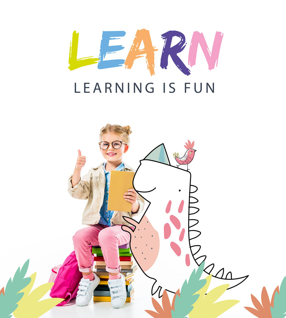 adorable élève souriant montrant pouce levé tout en étant assis sur une pile de livres avec dinosaure imaginaire isolé sur blanc avec lettrage "apprendre - apprendre est amusant"
 - Photo, image
