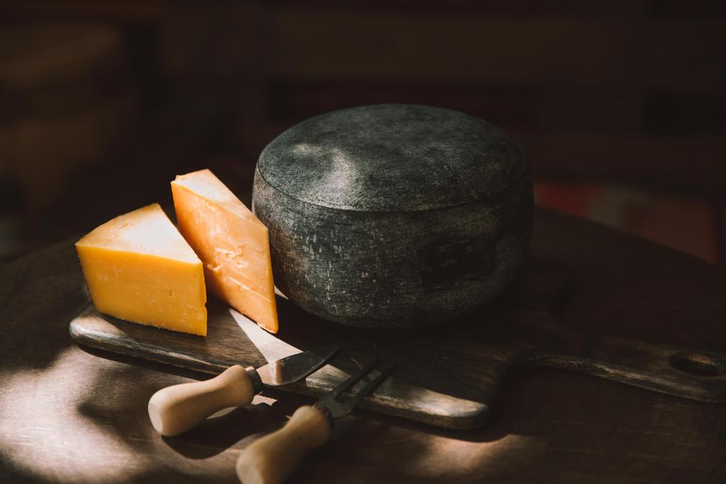 δύο είδη τυριών και μαχαιροπίρουνα σε ρουστίκ ξύλινα πίνακα - Φωτογραφία, εικόνα