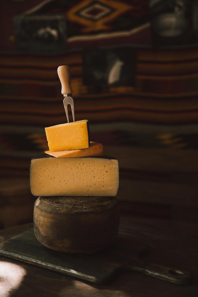 クローズ アップ ショットが詰まった素朴な木製のテーブルにフォークを様々 な種類のチーズのスライス - 写真・画像