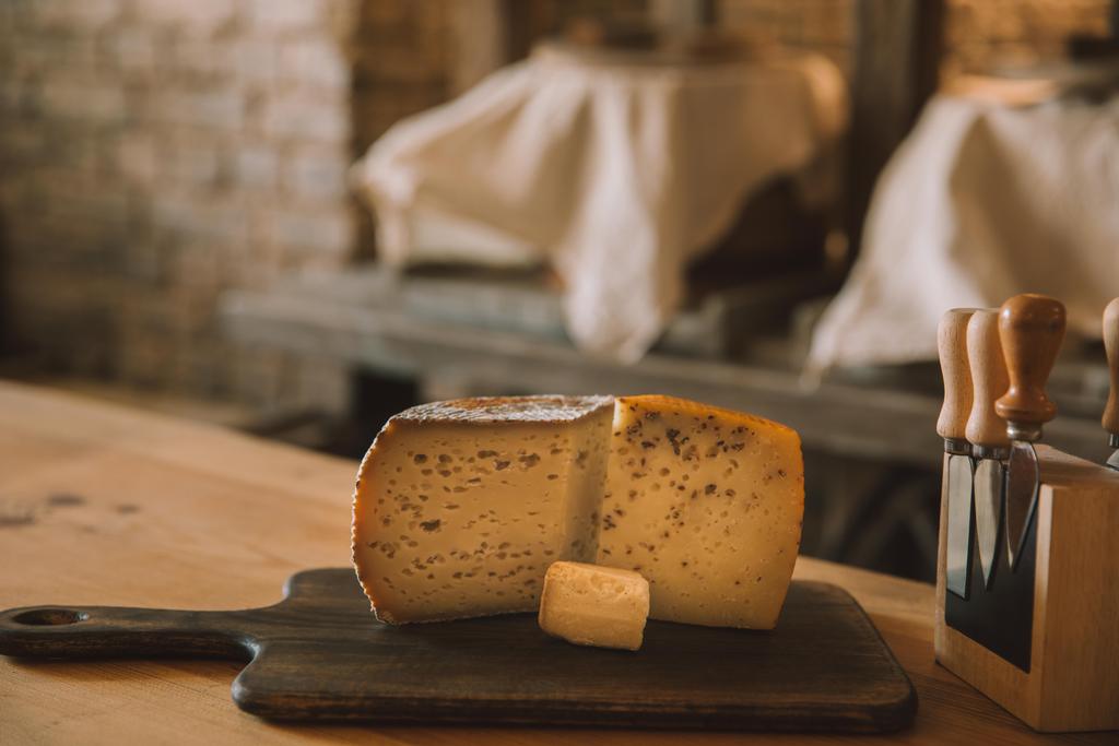 Detailní záběr plátkový sýr na prkénku s různými noži na stojan - Fotografie, Obrázek
