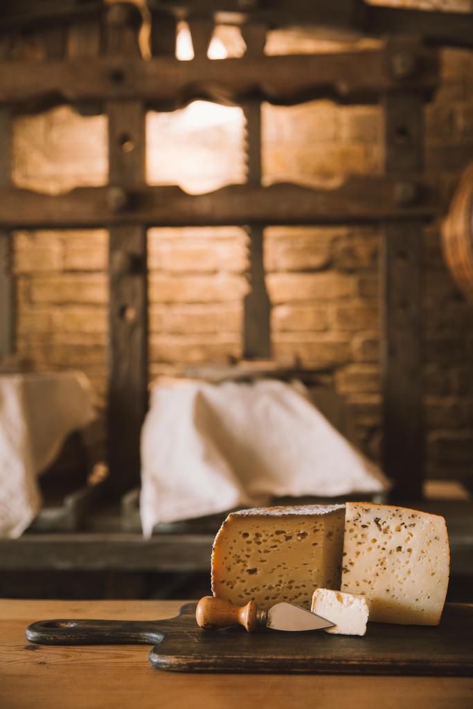 pochoutka, plátkový sýr s nožem na dřevěném prkénku - Fotografie, Obrázek