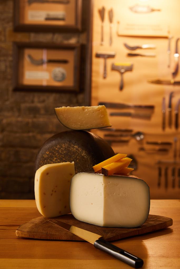 Nahaufnahme verschiedener Käsesorten mit Messer auf Holzbrettern - Foto, Bild
