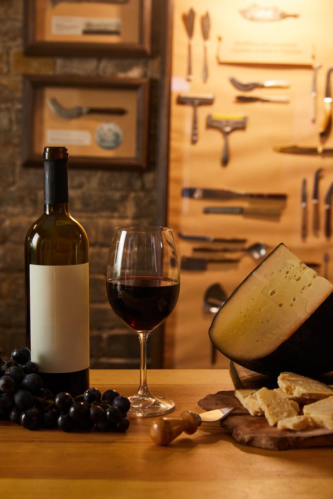 dilimlenmiş incelik peynir kırmızı şarap ve üzüm rustik tablo ile yakın çekim shot - Fotoğraf, Görsel