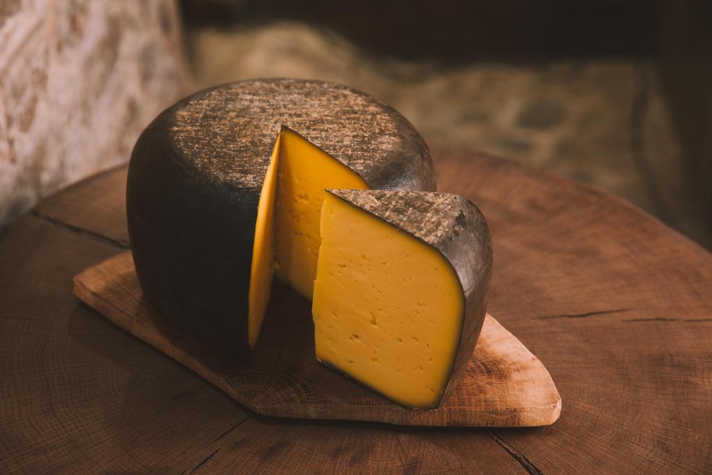 смачний нарізаний сир на сільській дерев'яній обробній дошці
 - Фото, зображення