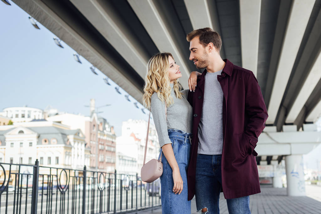 Zartes Paar im Herbst-Outfit schaut sich unter Brücke in der Stadt an - Foto, Bild