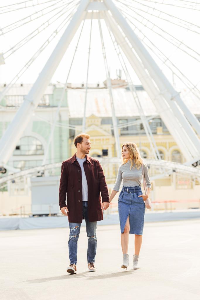 couple en tenue d'automne tenant la main et marchant près de la roue d'observation
 - Photo, image