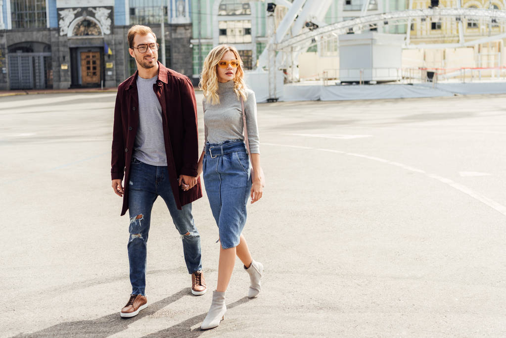 Stilvolles Paar im Herbst-Outfit hält Händchen und geht gemeinsam durch die Stadt - Foto, Bild
