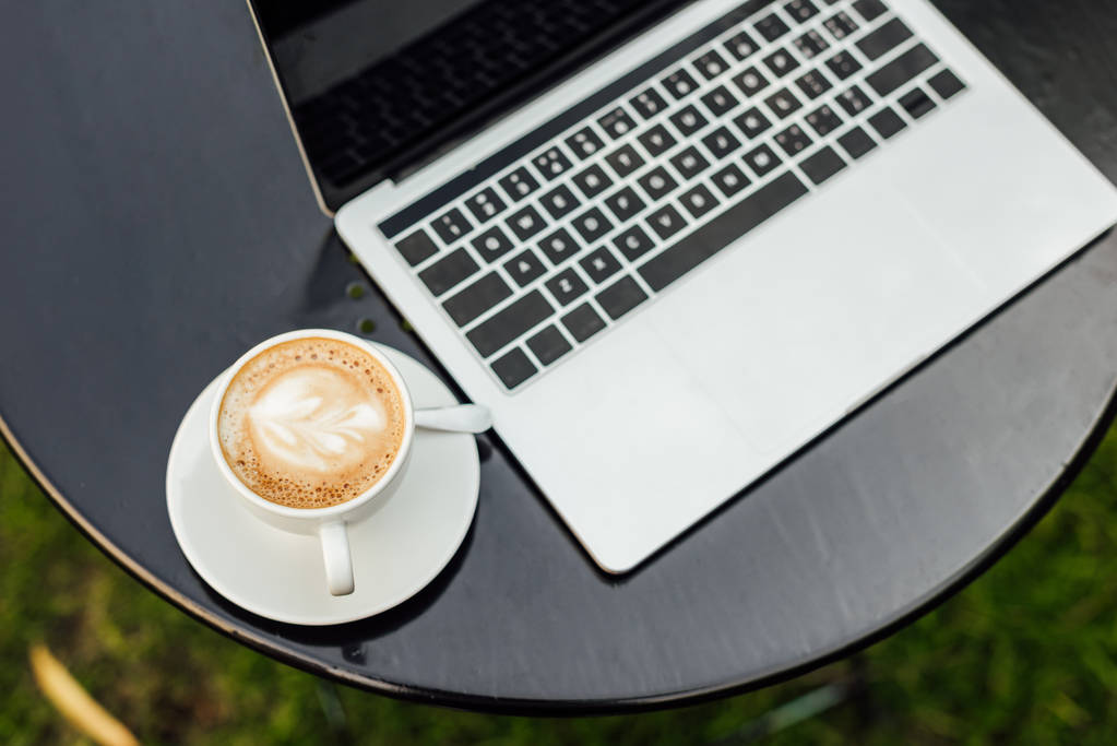 високий кут зору ноутбука і чашки кави на столі в саду
 - Фото, зображення