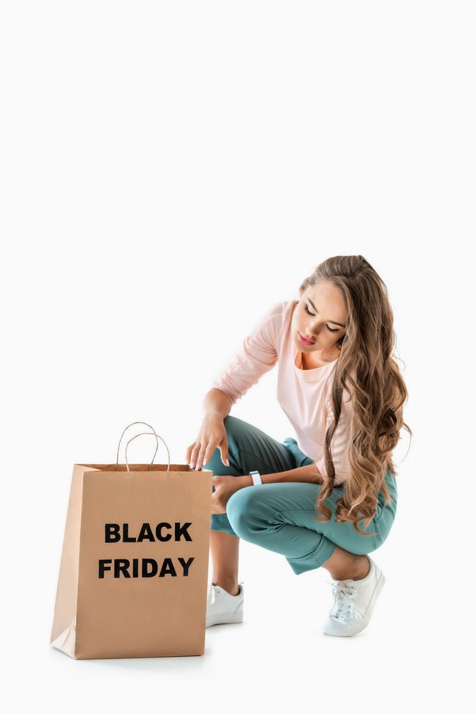 jolie fille regardant sac à provisions avec signe noir vendredi, isolé sur blanc
 - Photo, image