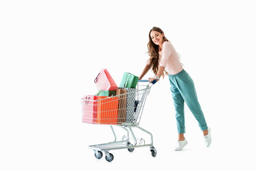 beautiful cheerful girl with shopping cart and bags, isolated on white - Photo, Image