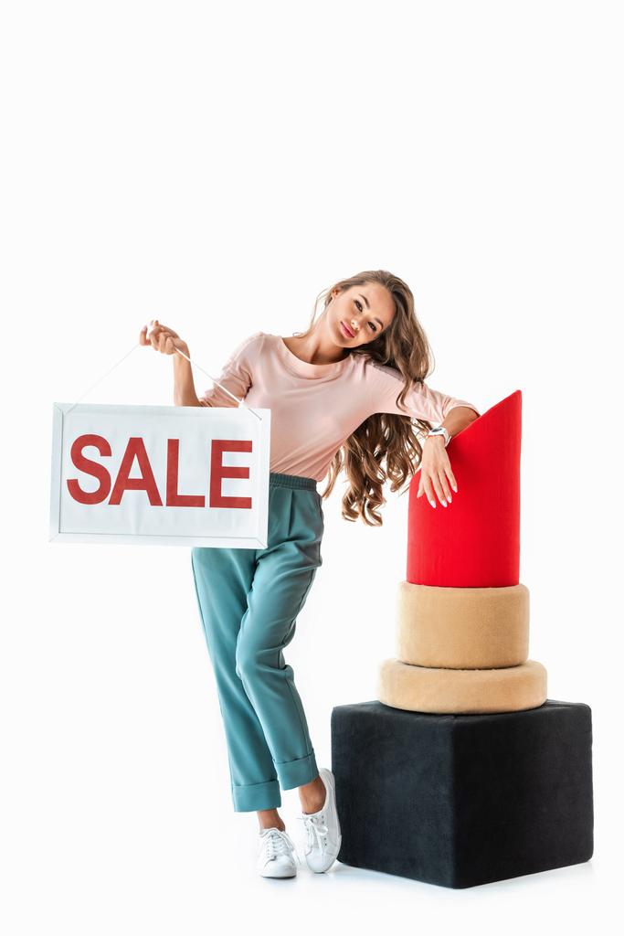 красивая женщина холдинг символ продажи рядом с большой красной помадой, концепция макияжа, изолированные на белом
  - Фото, изображение