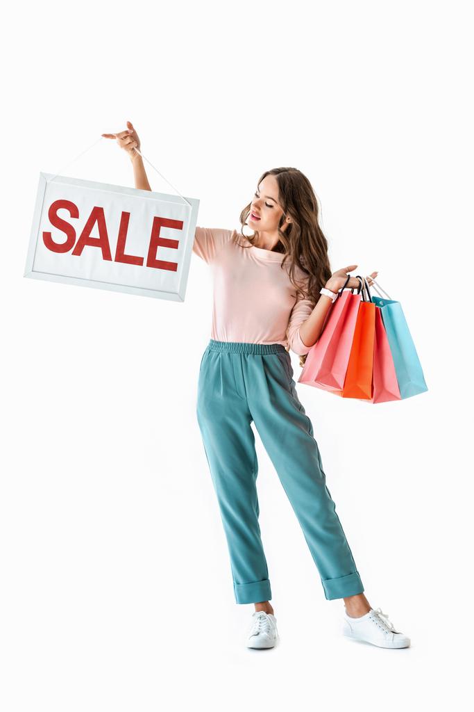 oříznutý pohled brunetka mladé ženy držící plovák s prodej znamení a nákupní tašky, izolované na bílém - Fotografie, Obrázek