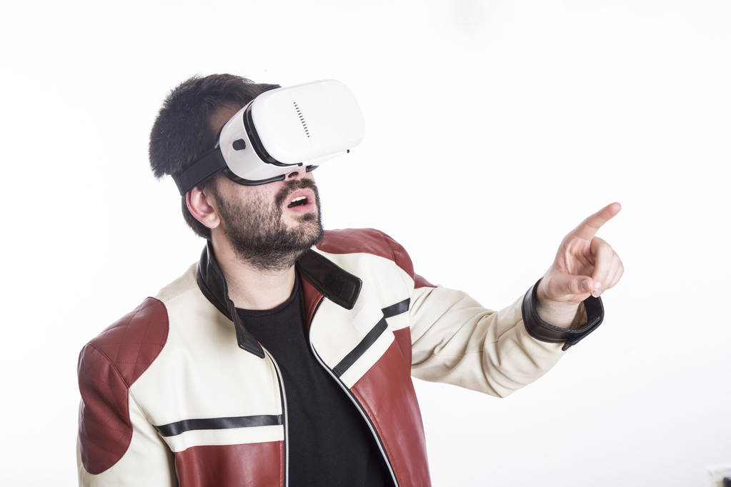 Mann trägt Virtual-Reality-Brille im weißen Studio und gestikuliert mit der Hand - Foto, Bild