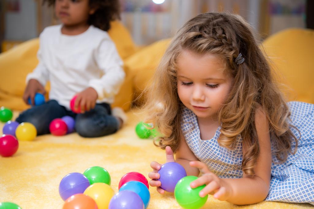 enfants multiculturels jouant avec des boules colorées sur le tapis à la maternelle
 - Photo, image
